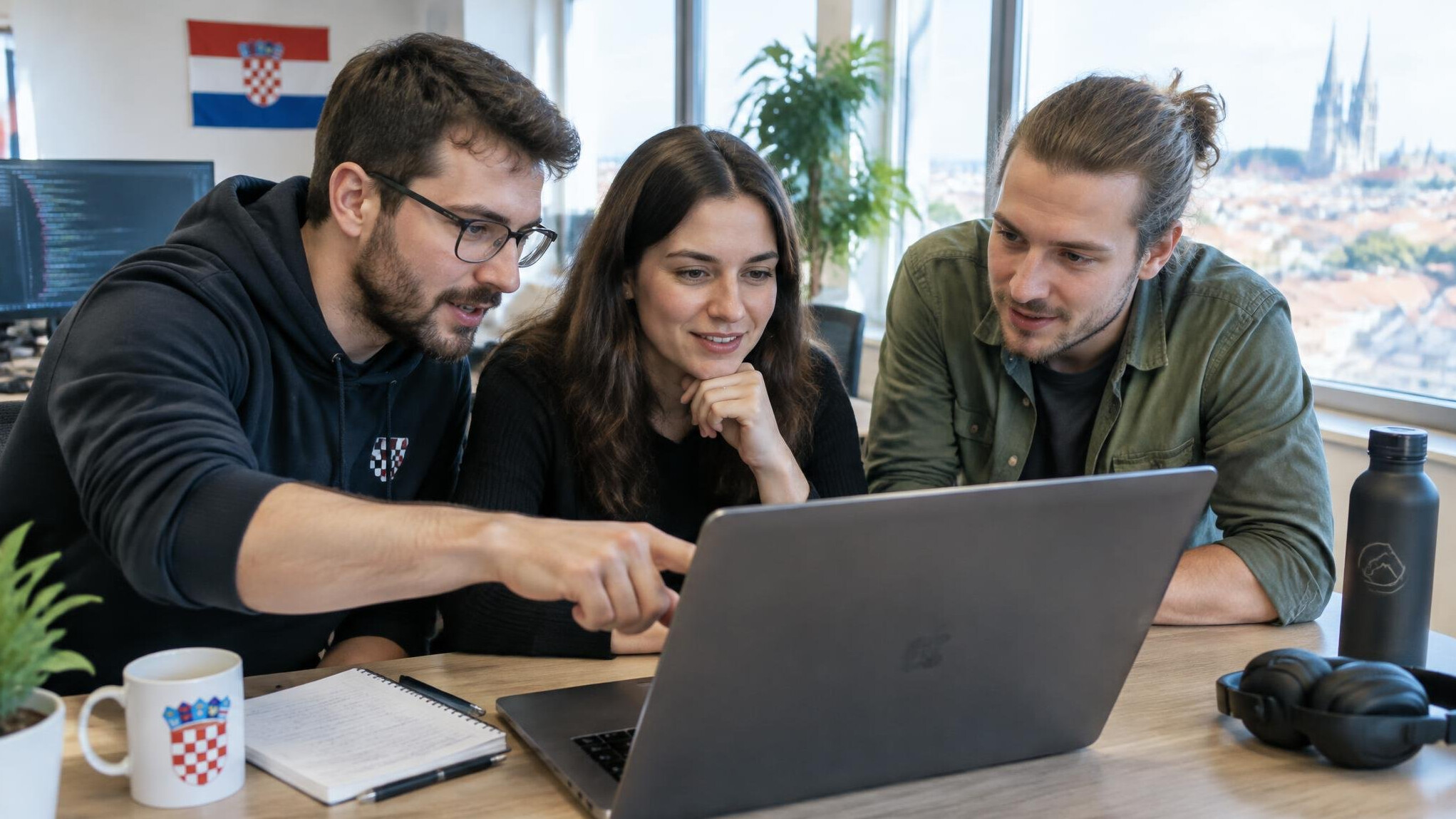 Group of developers collaborating around a laptop