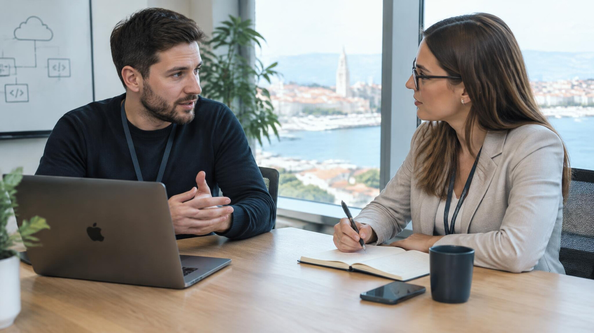 Two professionals discussing a project over a laptop in a meeting